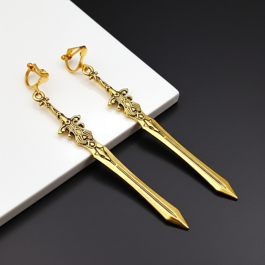 Clip on gold sword-shaped earrings on a dark surface