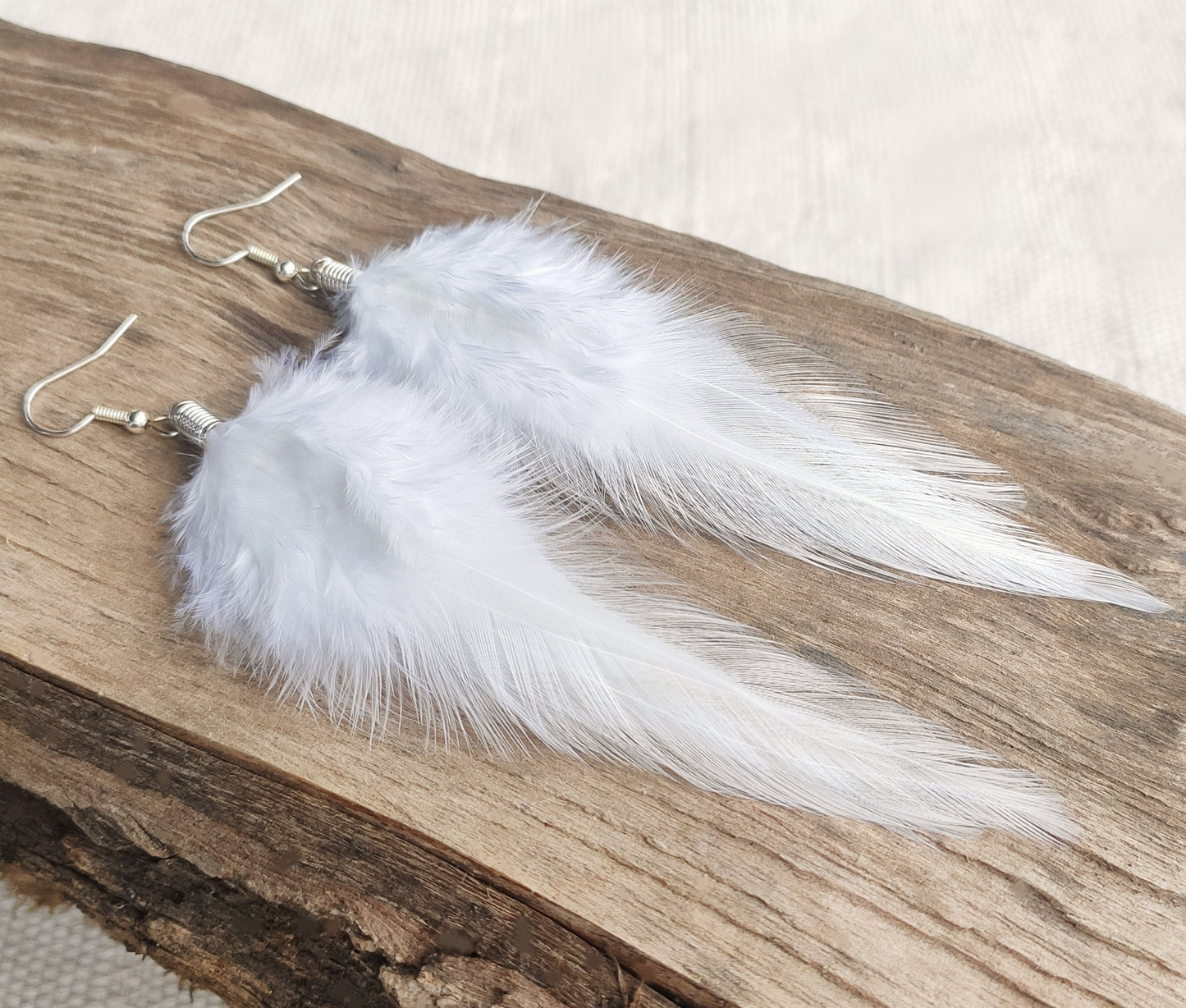 White feather earrings on a wooden surface