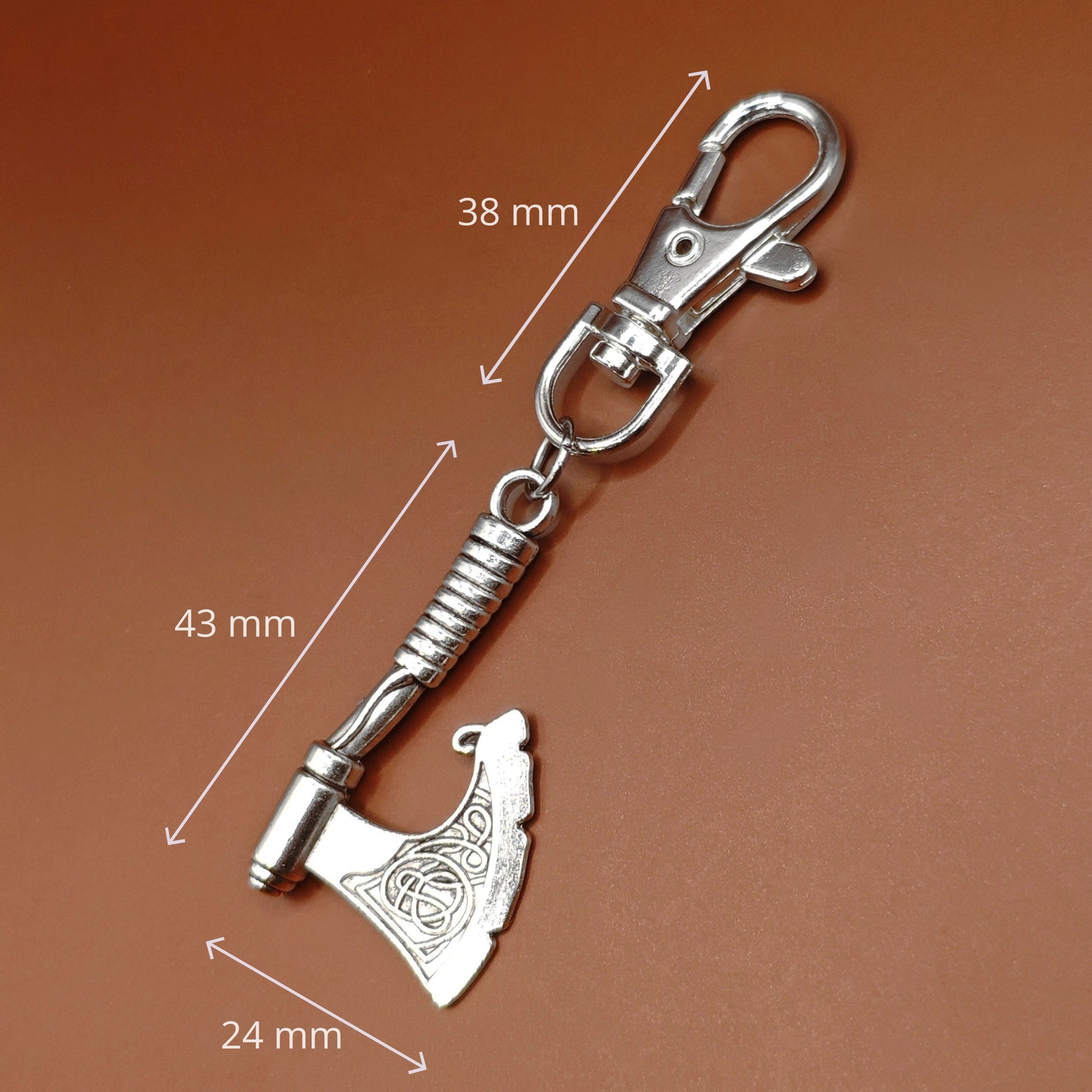 Silver axe keyring with measurements on a brown background