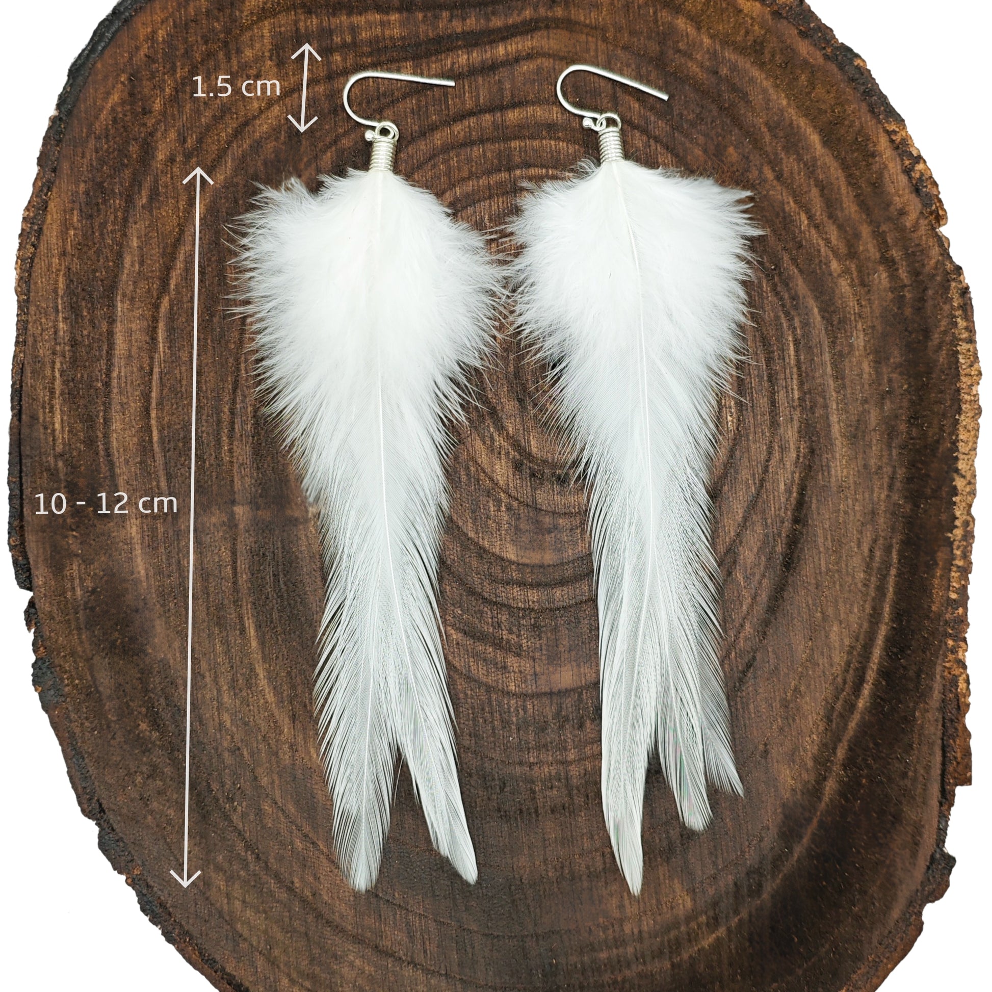 White feather earrings on a wooden background with measurements indicated.
