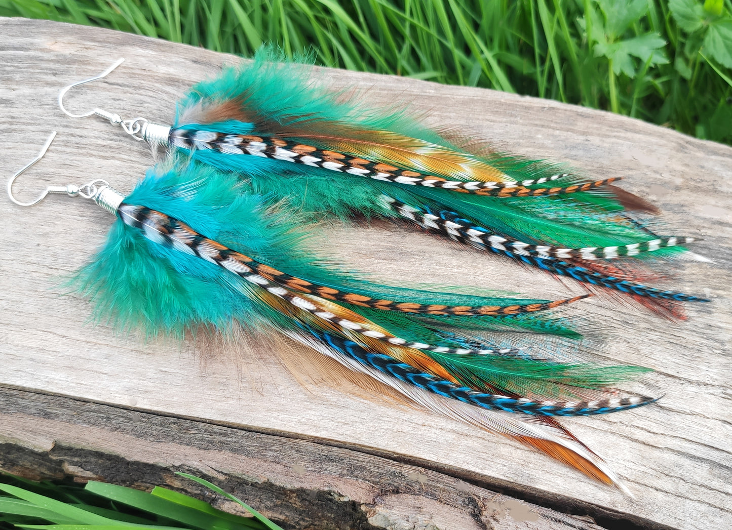 Long flowy dangly earrings made with colourful and stripy grizzly feathers.