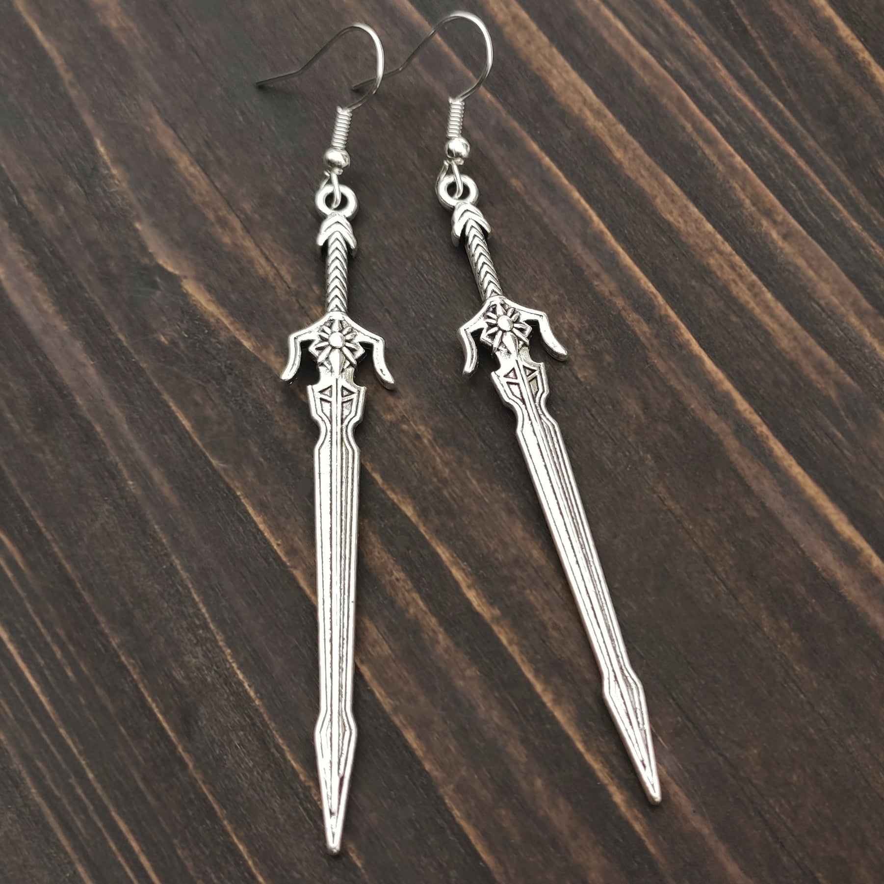 Cosplay-ready silver sword earrings with fantasy and LARP aesthetics. The long sword earrings have stainless steel hooks.