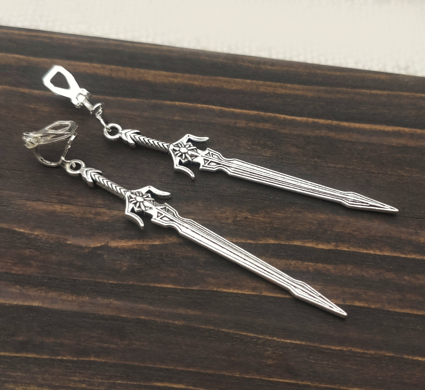 Cosplay-ready silver sword earrings with fantasy and LARP aesthetics. The long sword earrings have stainless steel clip ons.