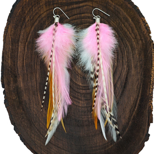 Pink feather earrings with silver hooks on a wooden background. Boho hippie style.