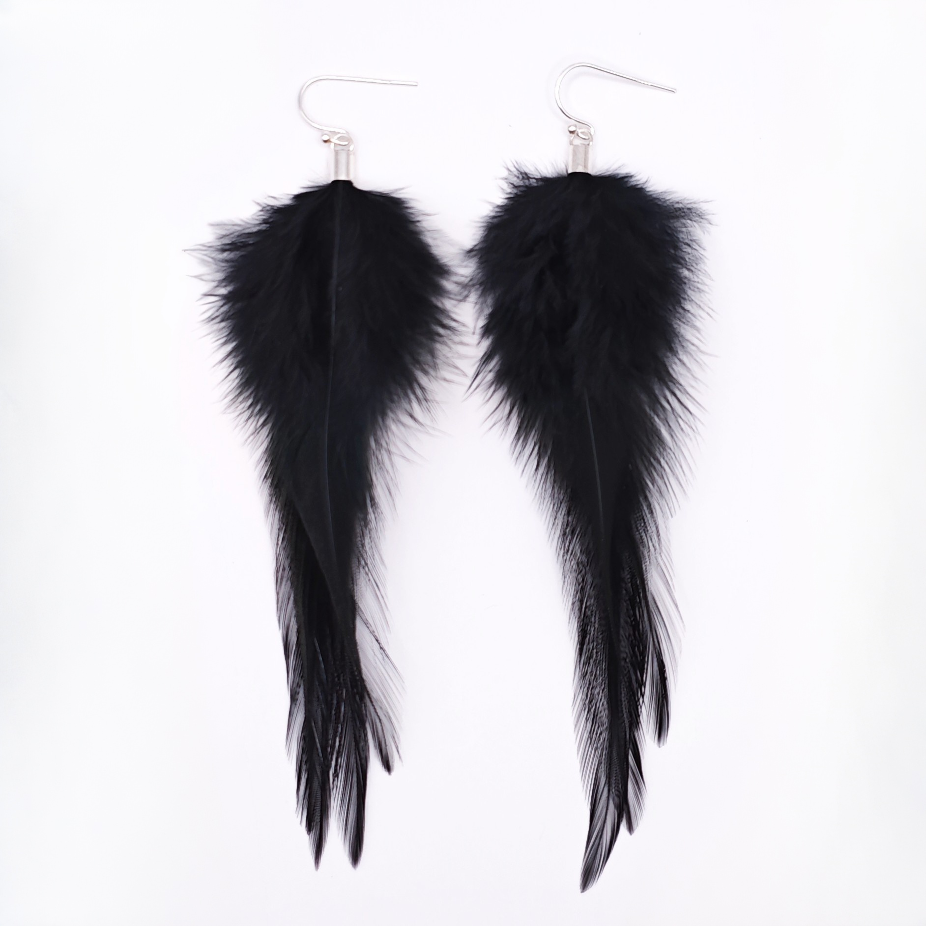 Black feather earrings with silver hooks on a white background. Gothic jewelry
