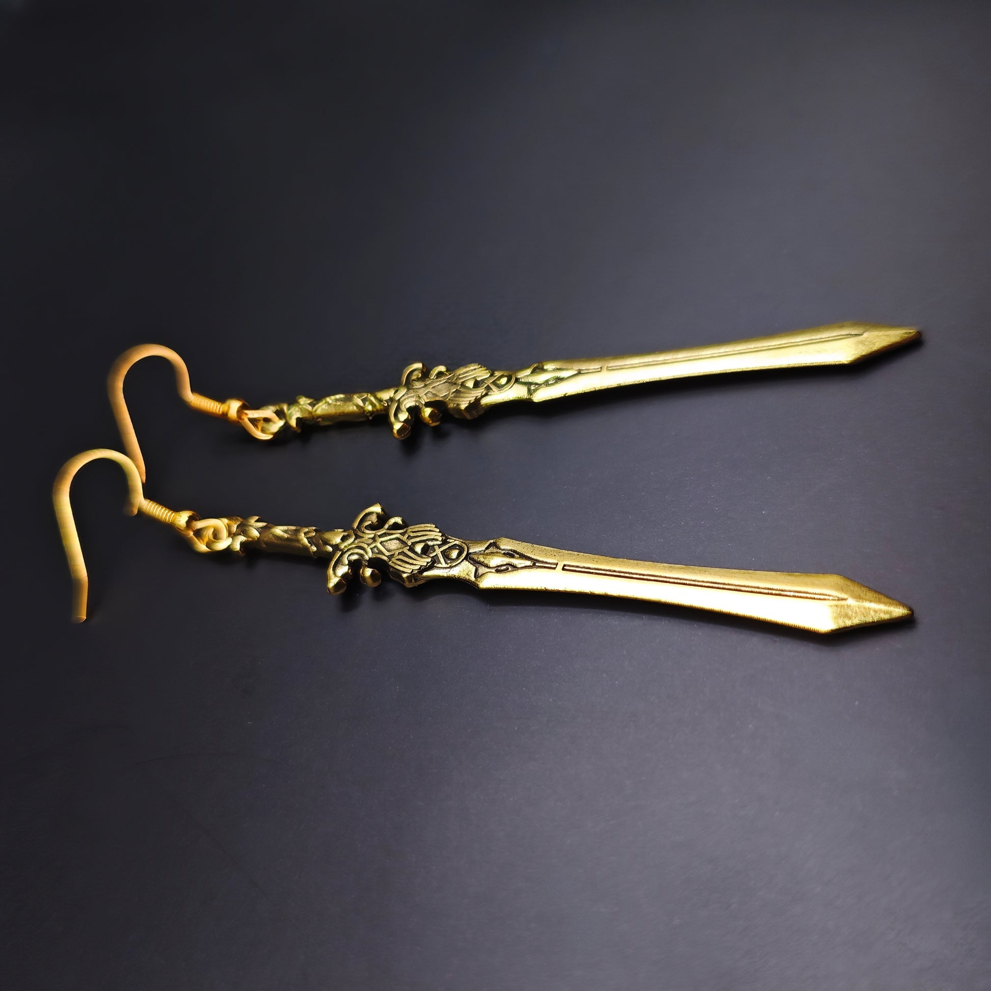Long gold sword earrings with stainless steel hooks. The swords have a fantasy medieval style and look like historical renaissance weapons.