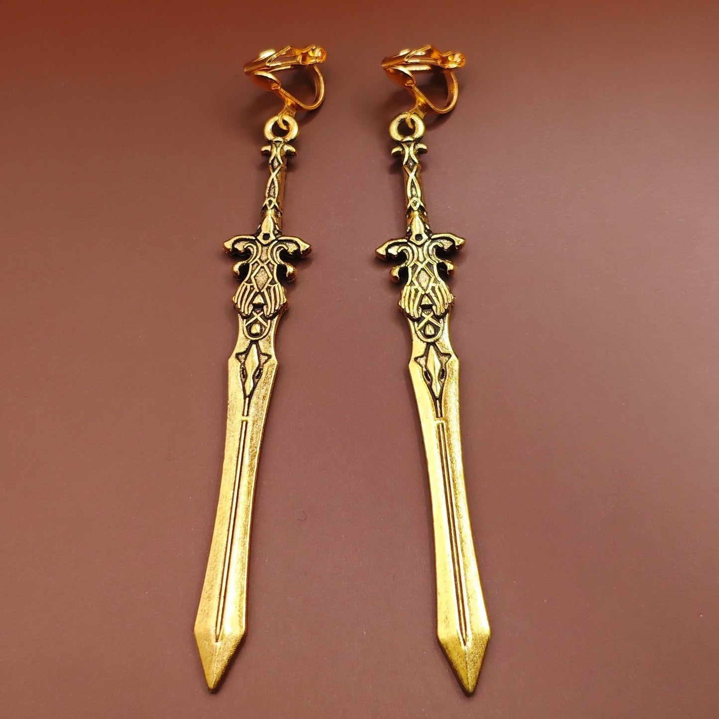 Gold clip on sword earrings with fantasy design. A unique gift for RPG players, LARP fans, or gamers.
