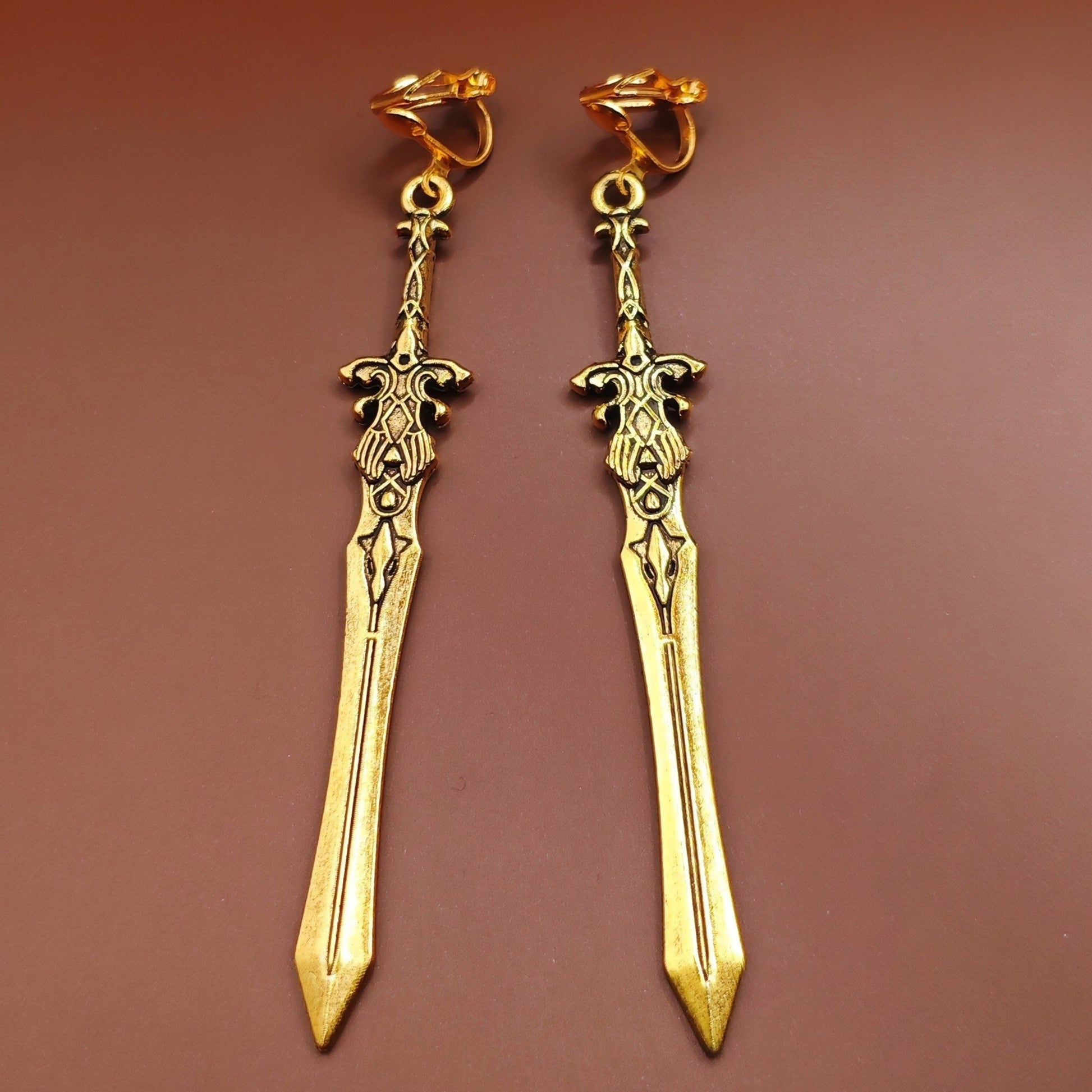 Gold clip on sword earrings with fantasy design. A unique gift for RPG players, LARP fans, or gamers.