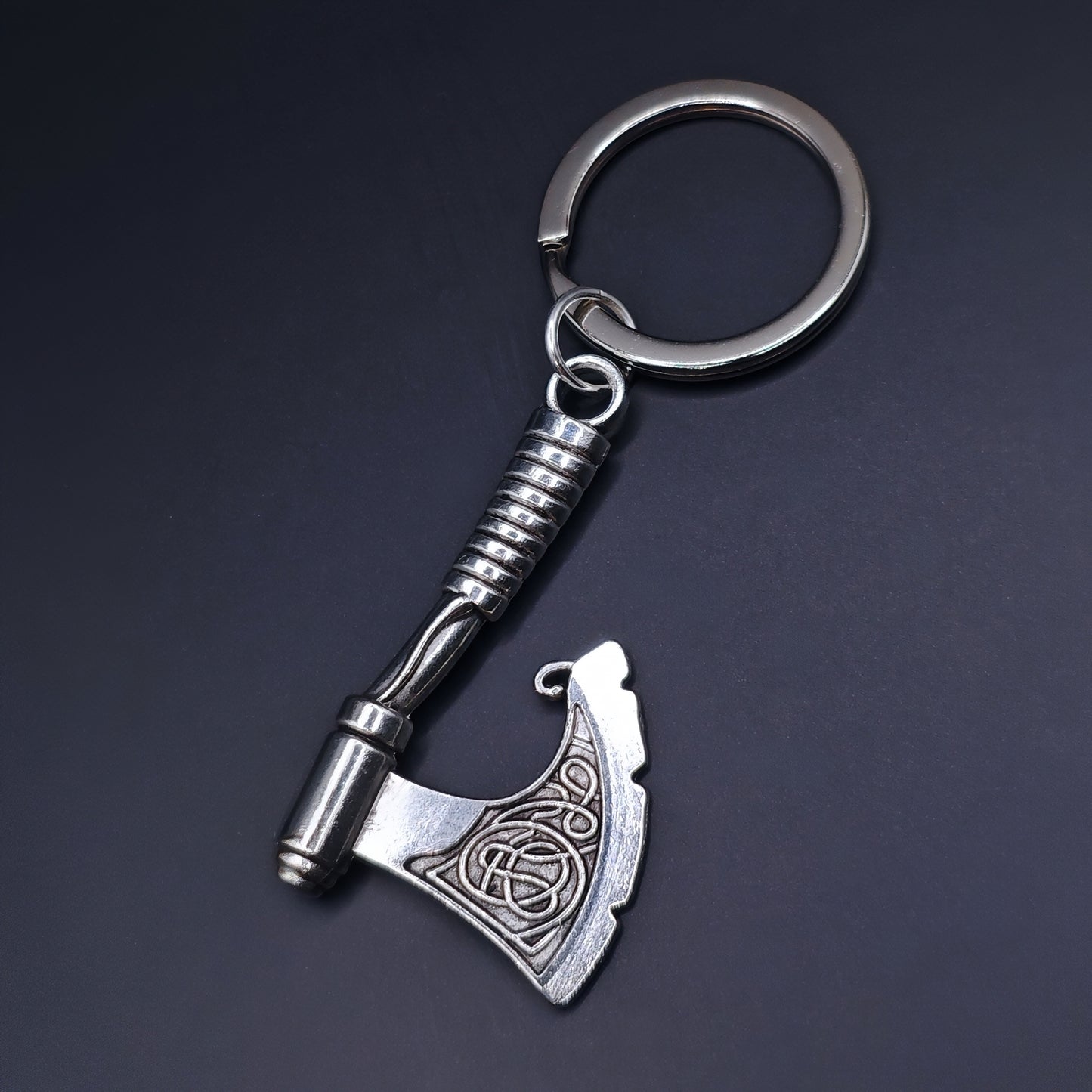 Silver celtic style axe keychain on a dark background