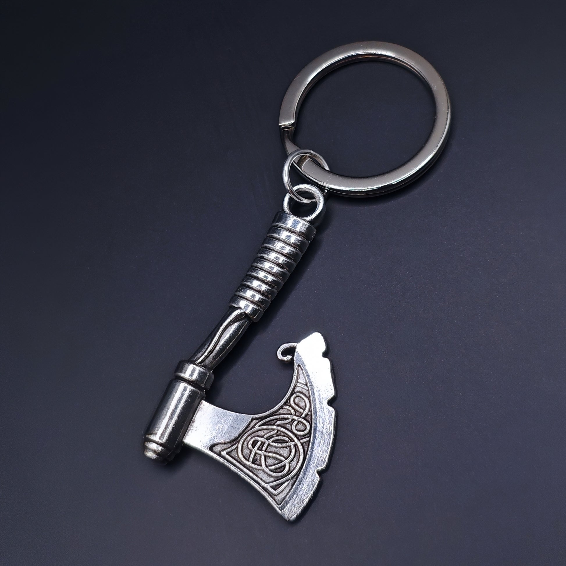 Silver celtic style axe keychain on a dark background