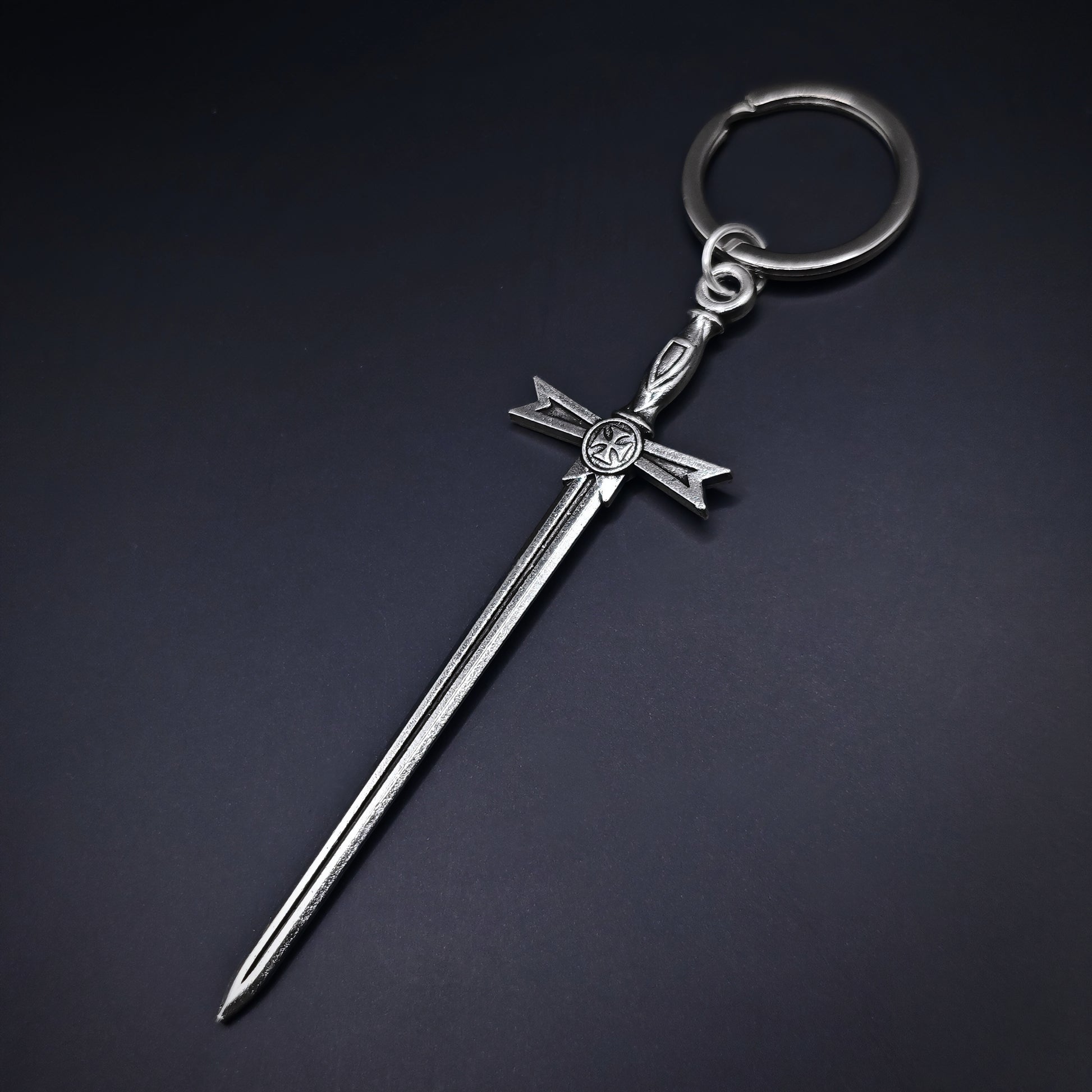 Silver keychain with a medieval sword design on a dark background