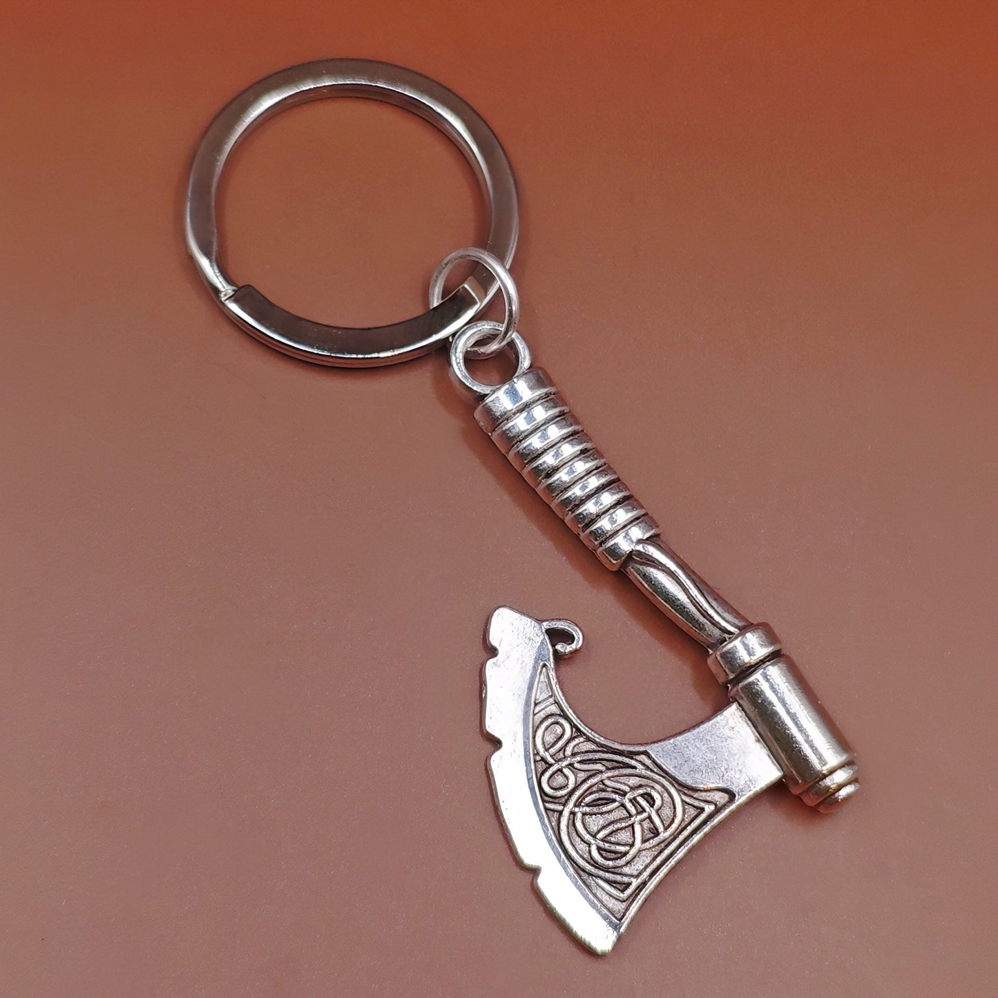 Silver keychain with fantasy axe design on a brown background