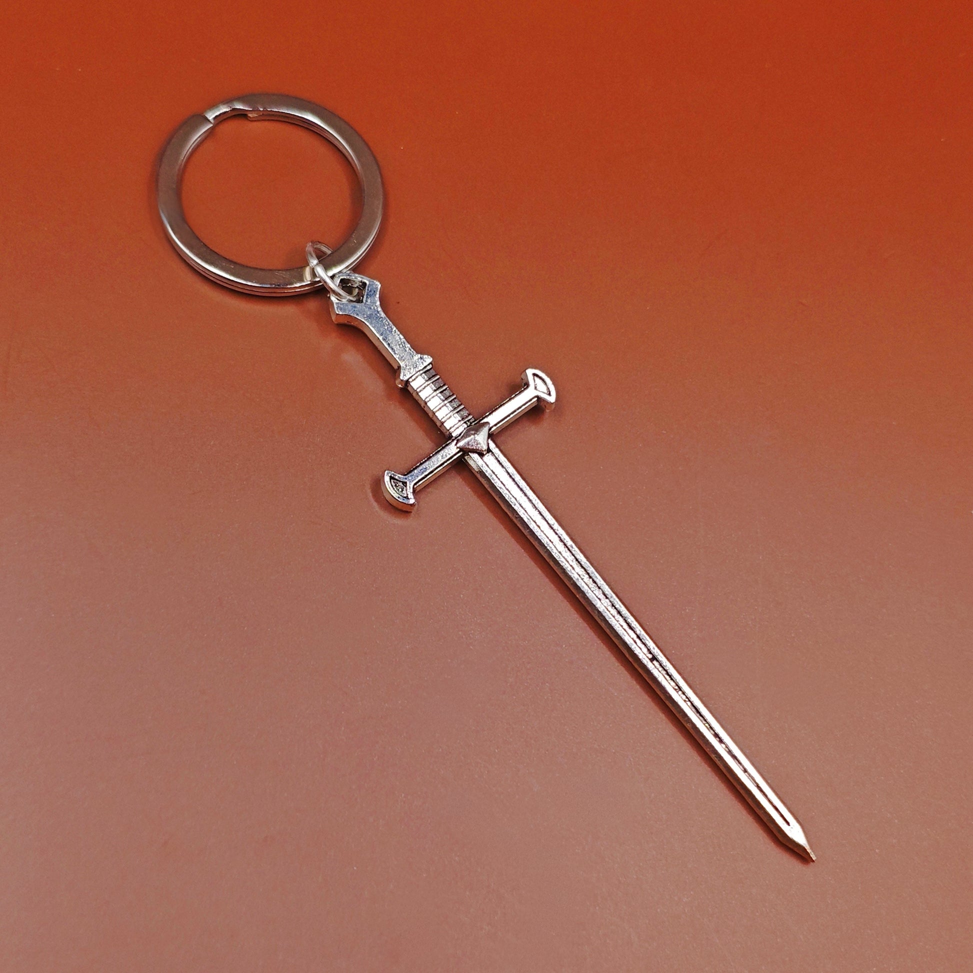 Fantasy style silver sword keychain on a red background