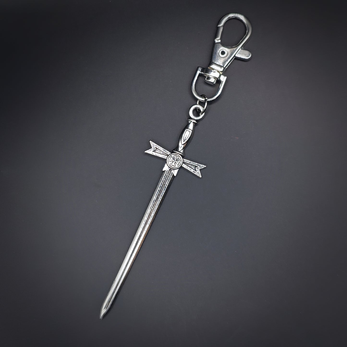 Silver sword-shaped keychain on a dark gray background
