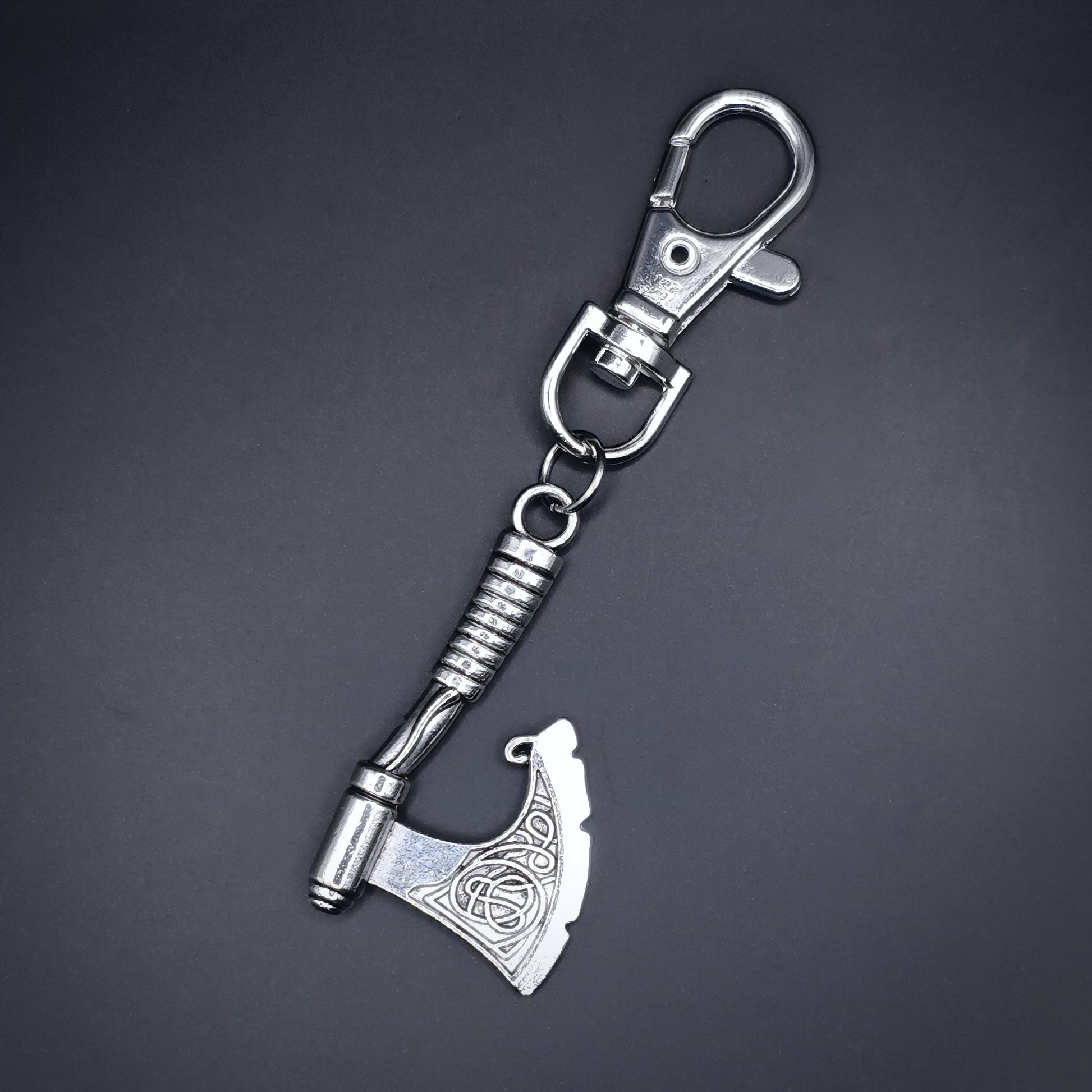 Silver axe keychain on a dark gray background. Fantasy viking style.