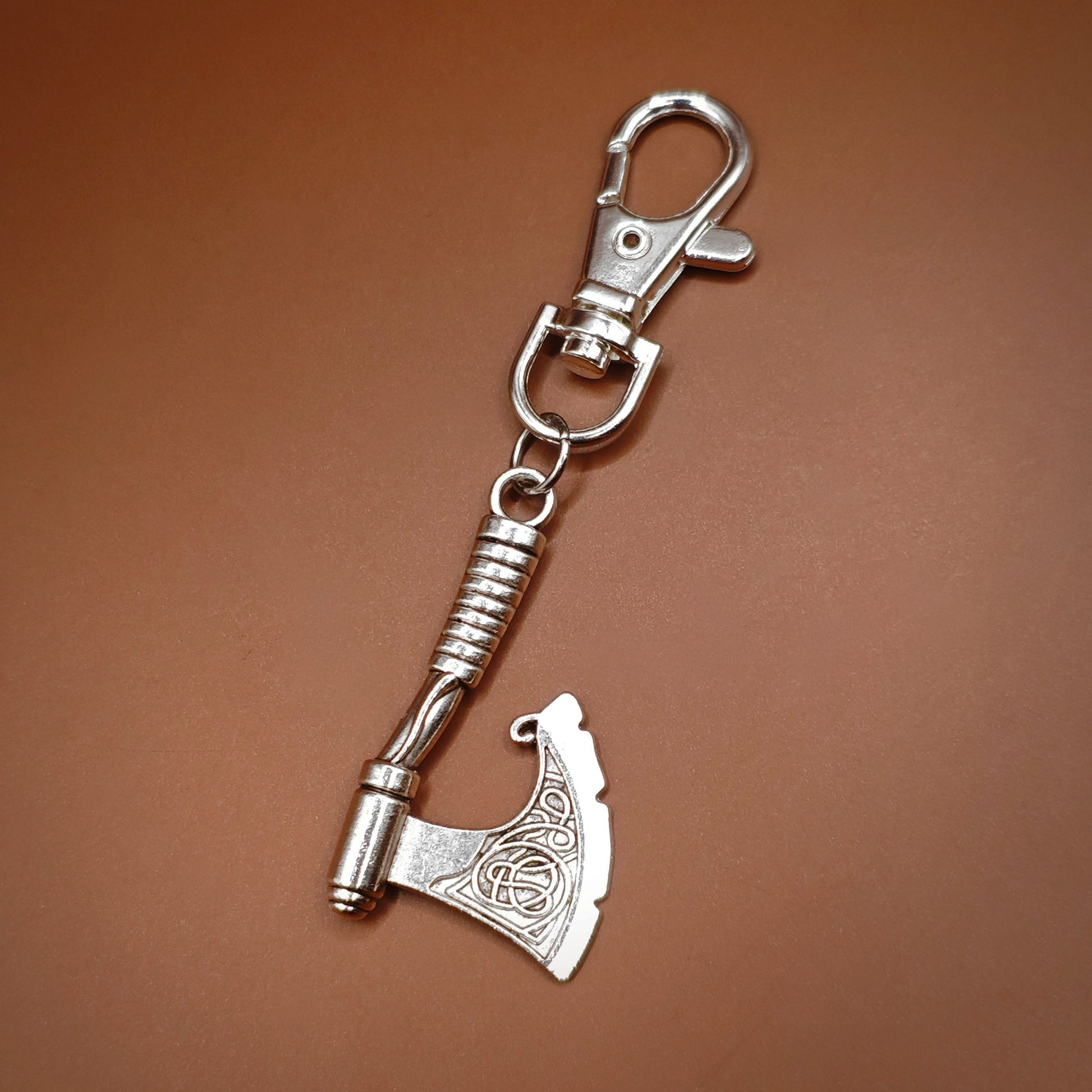 Silver axe-shaped keychain with a clasp on a brown background