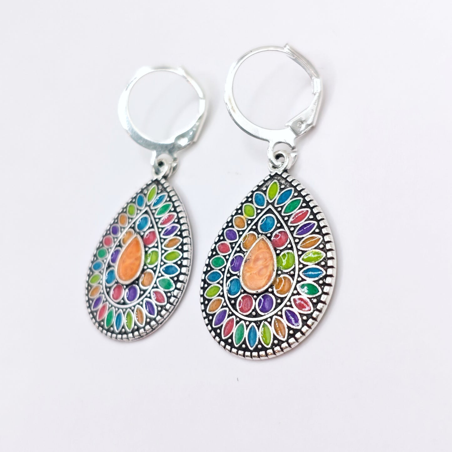 Side view of multicolored bohemian dangle earrings with silver hoops.