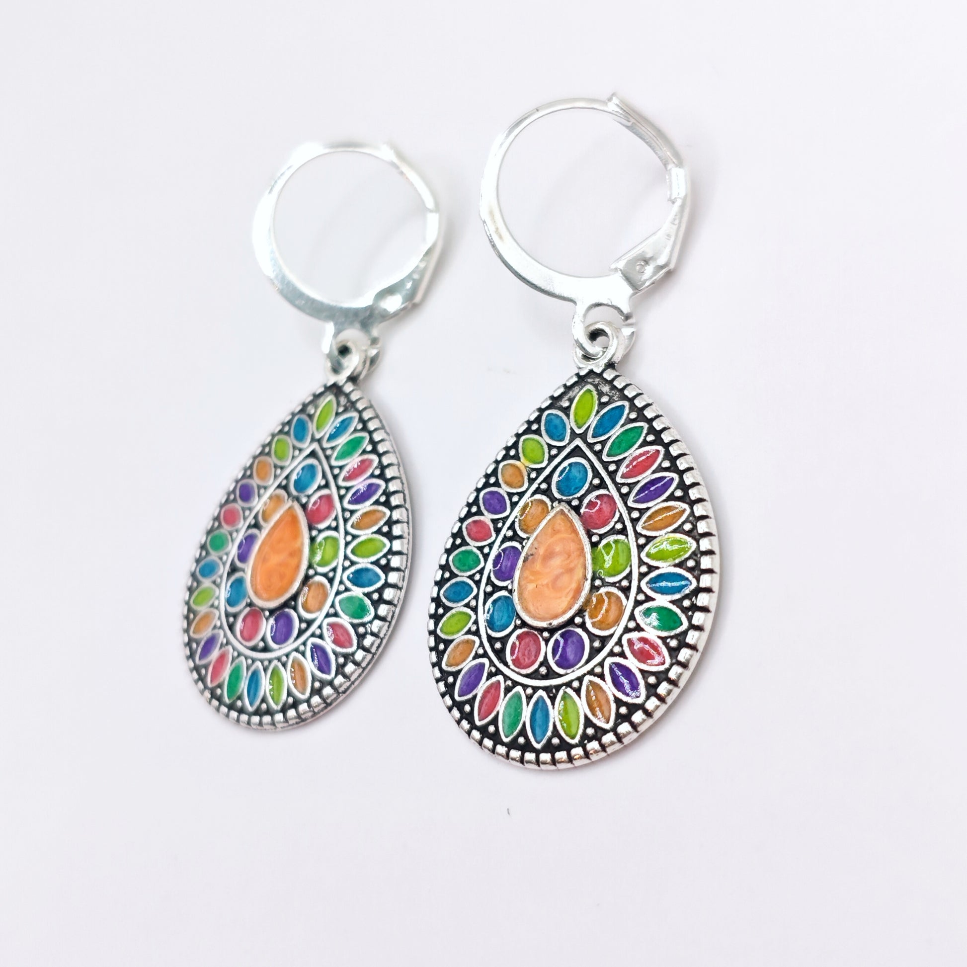 Side view of multicolored bohemian dangle earrings with silver hoops.