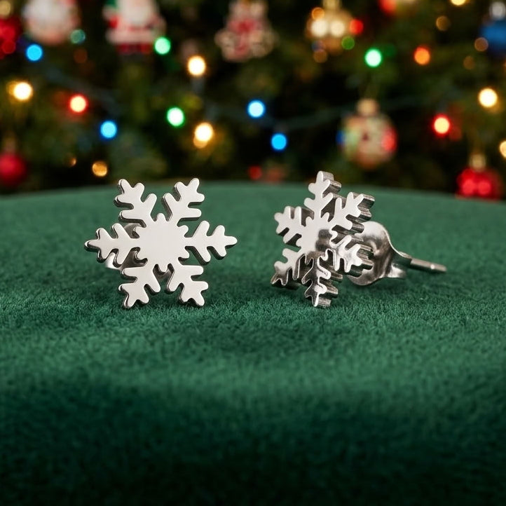 Dainty snowflake stud earrings made from stainless steel on a green velvet background with festive lights in the background.