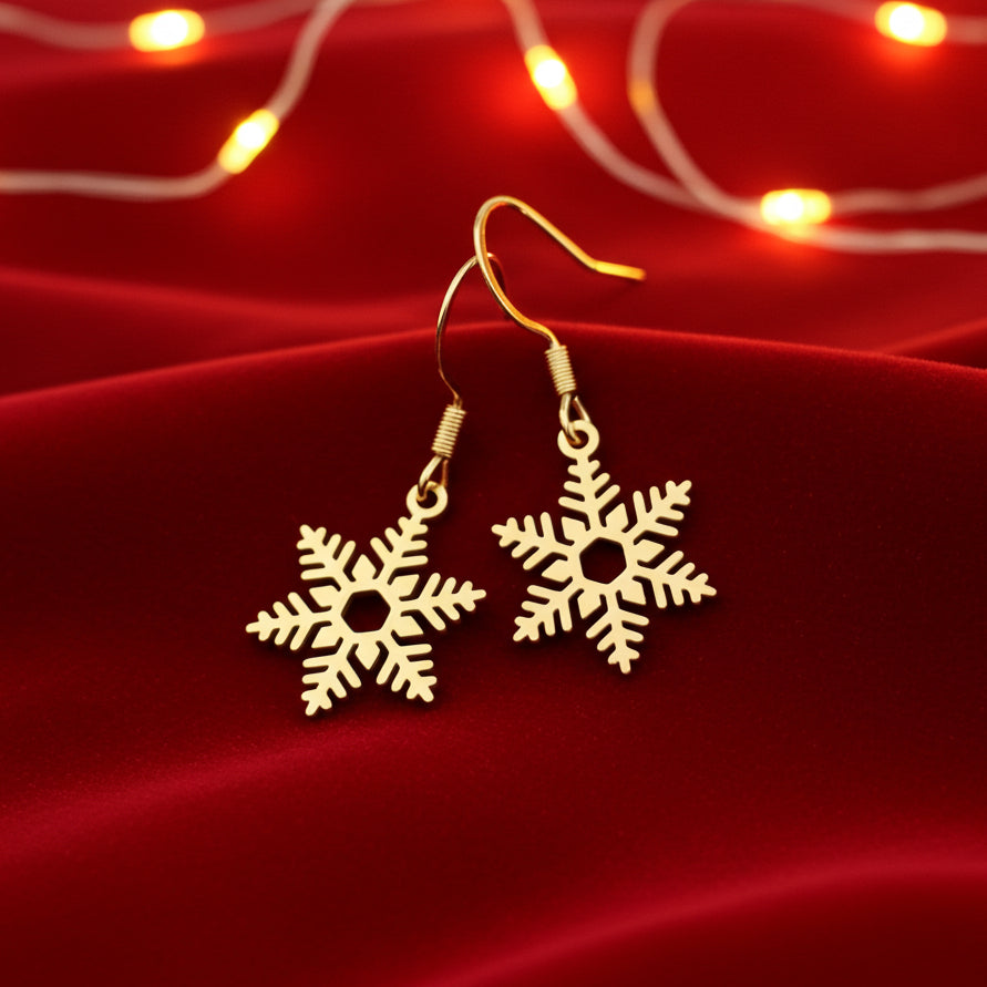 Gold snowflake earrings on a red fabric background with string lights.