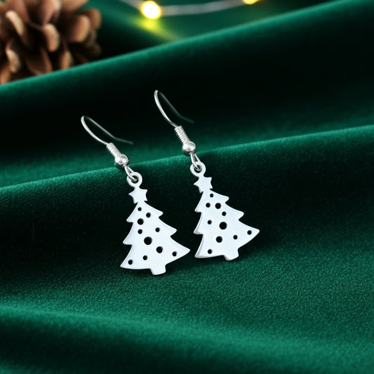 Festive Christmas tree earrings with hooks made from silver stainless steel on green velvet with lights in the background.