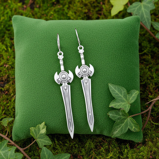 Silver sword earrings on a green cushion with leaves in the background