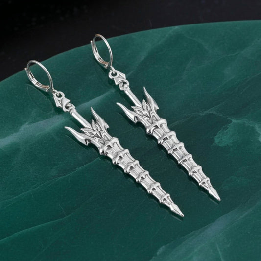 Fantasy silver sword earrings with hoops on a green marble background