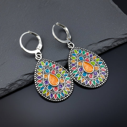 Colorful earrings with a silver frame on a dark stone surface