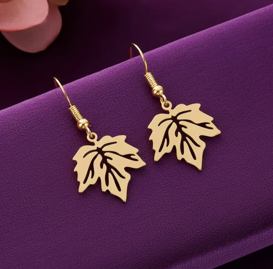 Gold stainless steel leaf earrings with hooks on a purple background