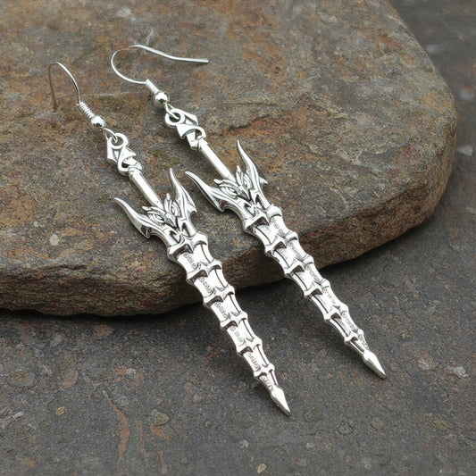Fantasy silver sword earrings with hooks on a stone background