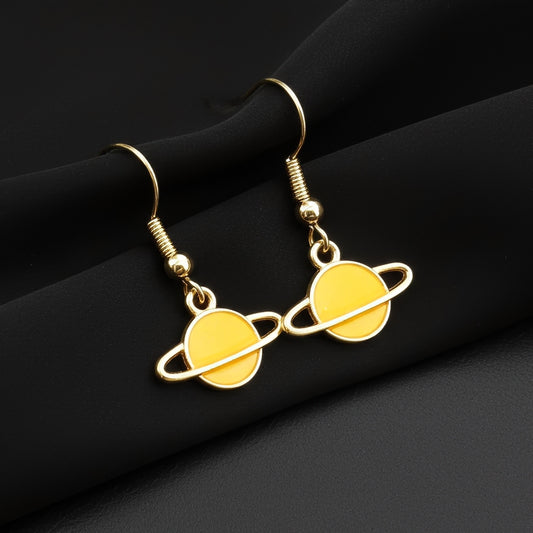 Yellow Saturn planet earrings with gold hooks on a black background