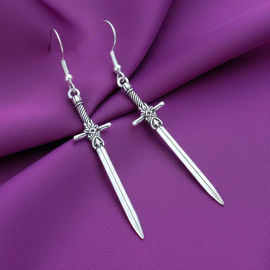 Fantasy style silver sword earrings on a purple fabric background