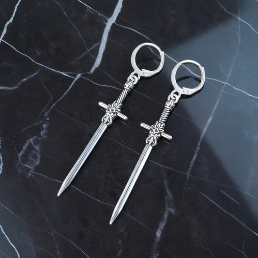 Fantasy style silver sword earrings with hoops on a black marble background