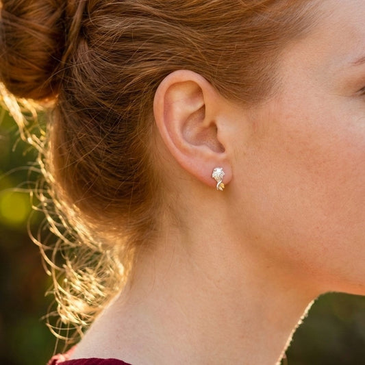 A woman wearing a silver fish stud earrings with gold tails