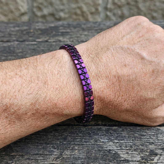Close-up of a wrist wearing a purple beaded bracelet on a wooden surface.