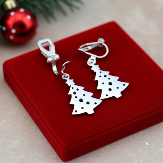 Festive Christmas tree earrings with clip-ons made from silver stainless steel on red velvet with lights in the background.