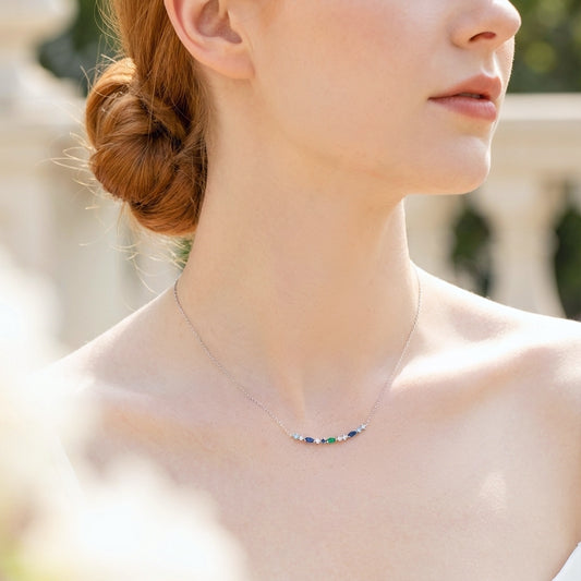 A woman in the sunshine wearing a dainty necklace made with 925 sterling silver and coloured small gemstones