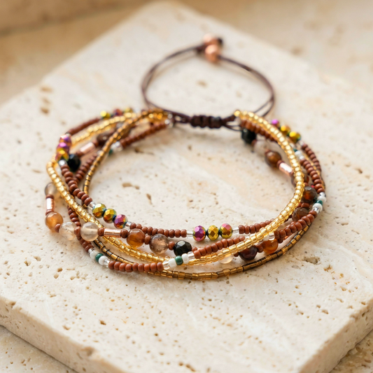 Multiple beaded bracelet with 5 layers of gold and brown beads tied together, on a light stone background. Boho rustic style
