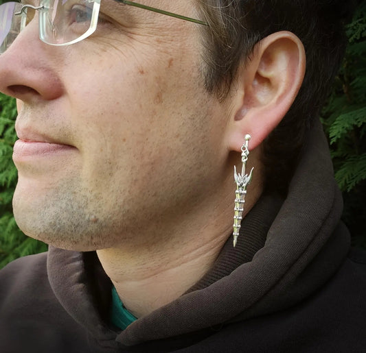 A man wearing silver sword earrings with clip-ons