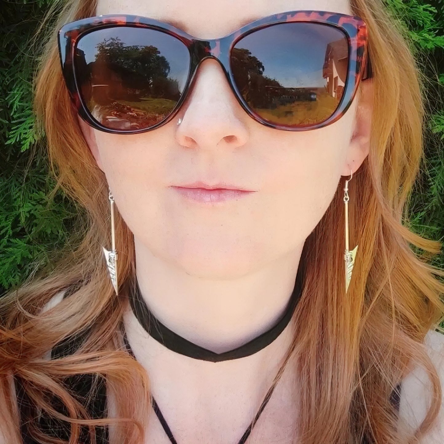 Woman wearing silver fantasy sword earrings with a blurred natural background