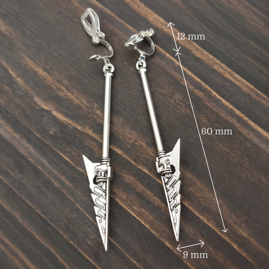 Silver spear/axe earrings with measurements on a wooden surface