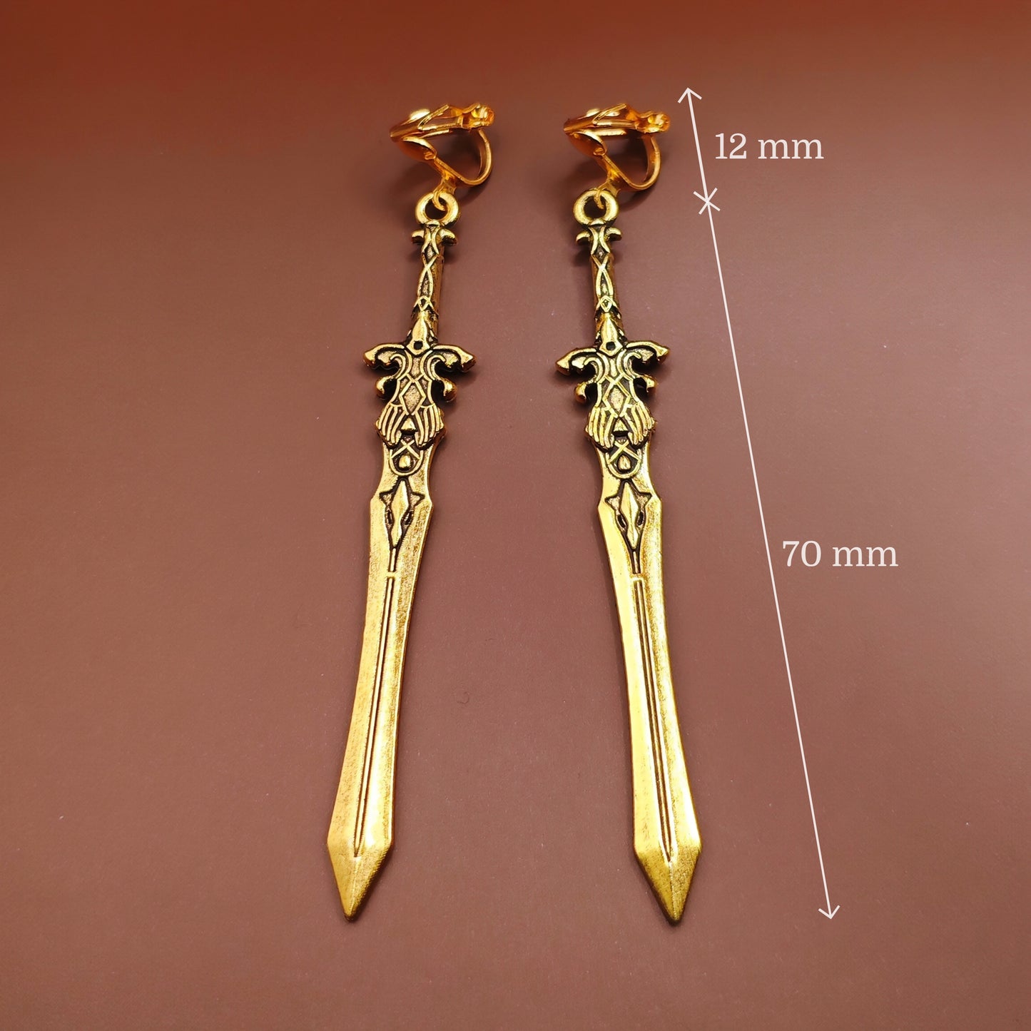 Gold sword earrings with measurements on a brown background. Great for cosplay or costumes.