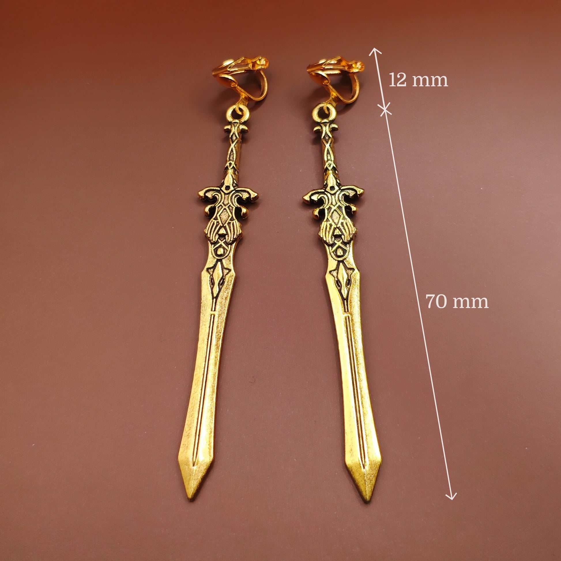 Gold sword earrings with measurements on a brown background. Great for cosplay or costumes.