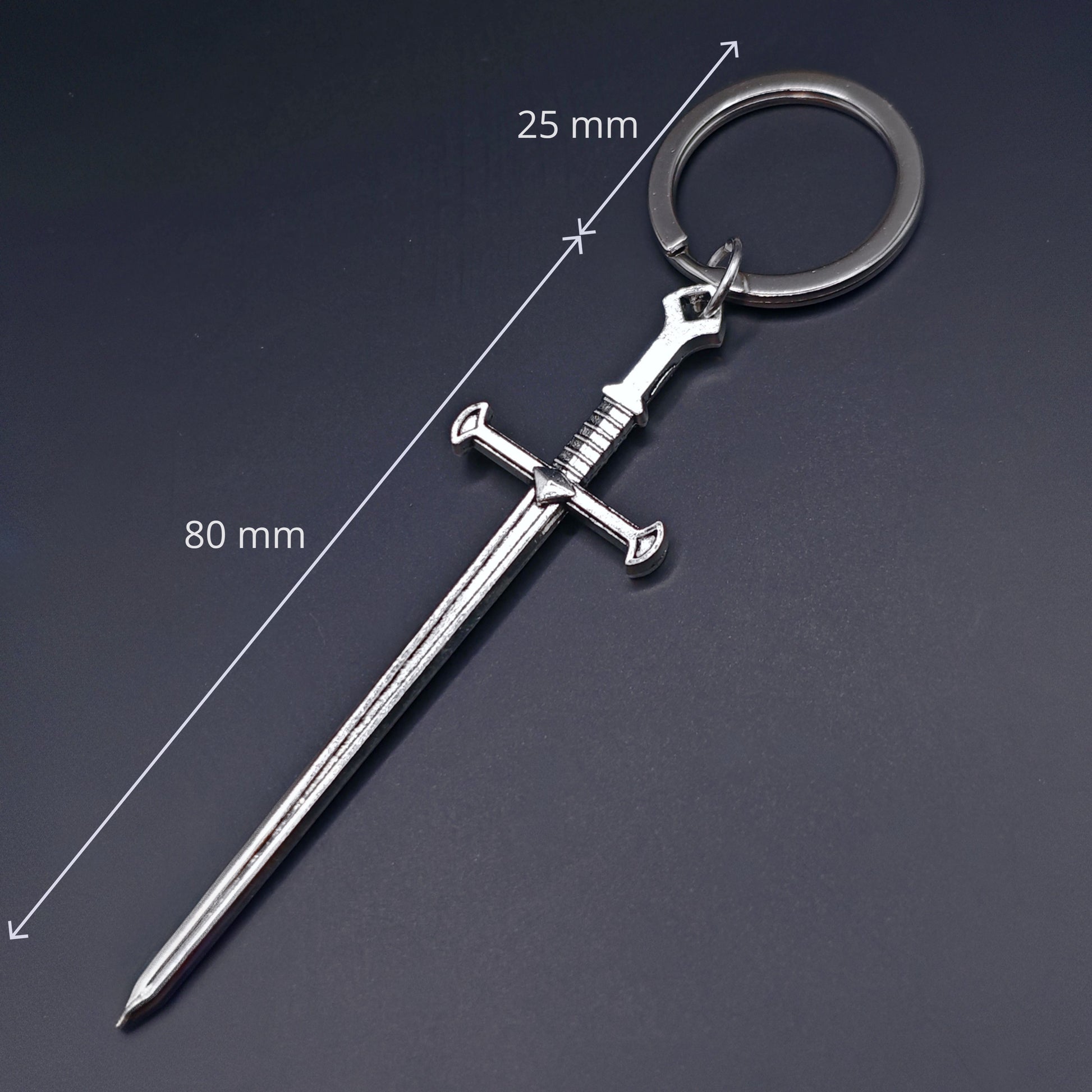 Sword-shaped keychain with measurements on a dark background