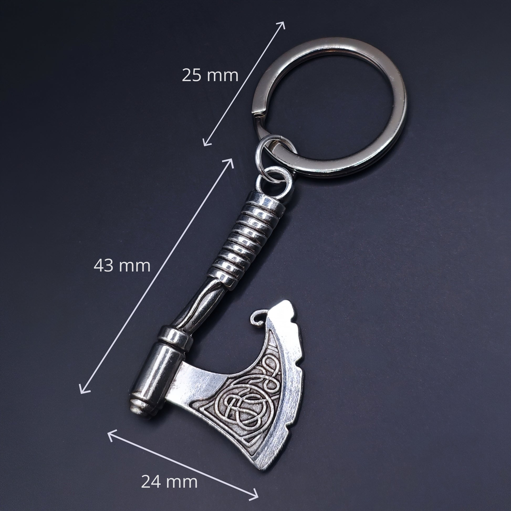 Silver keychain with axe design and measurements on a dark background