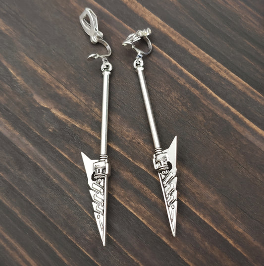 Silver arrowhead-shaped sword clip on earrings on a wooden surface. Fantasy battle mace jewelry