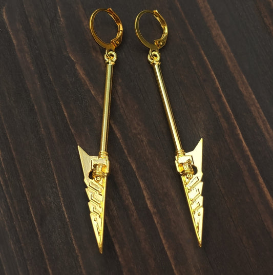 Gold arrow-shaped sword/axe earrings with hoops on a dark wooden surface. Fantasy mace jewelry