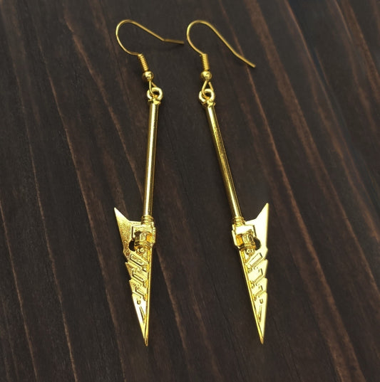 Gold arrowhead sword earrings on a wooden surface, fantasy axe jewelry