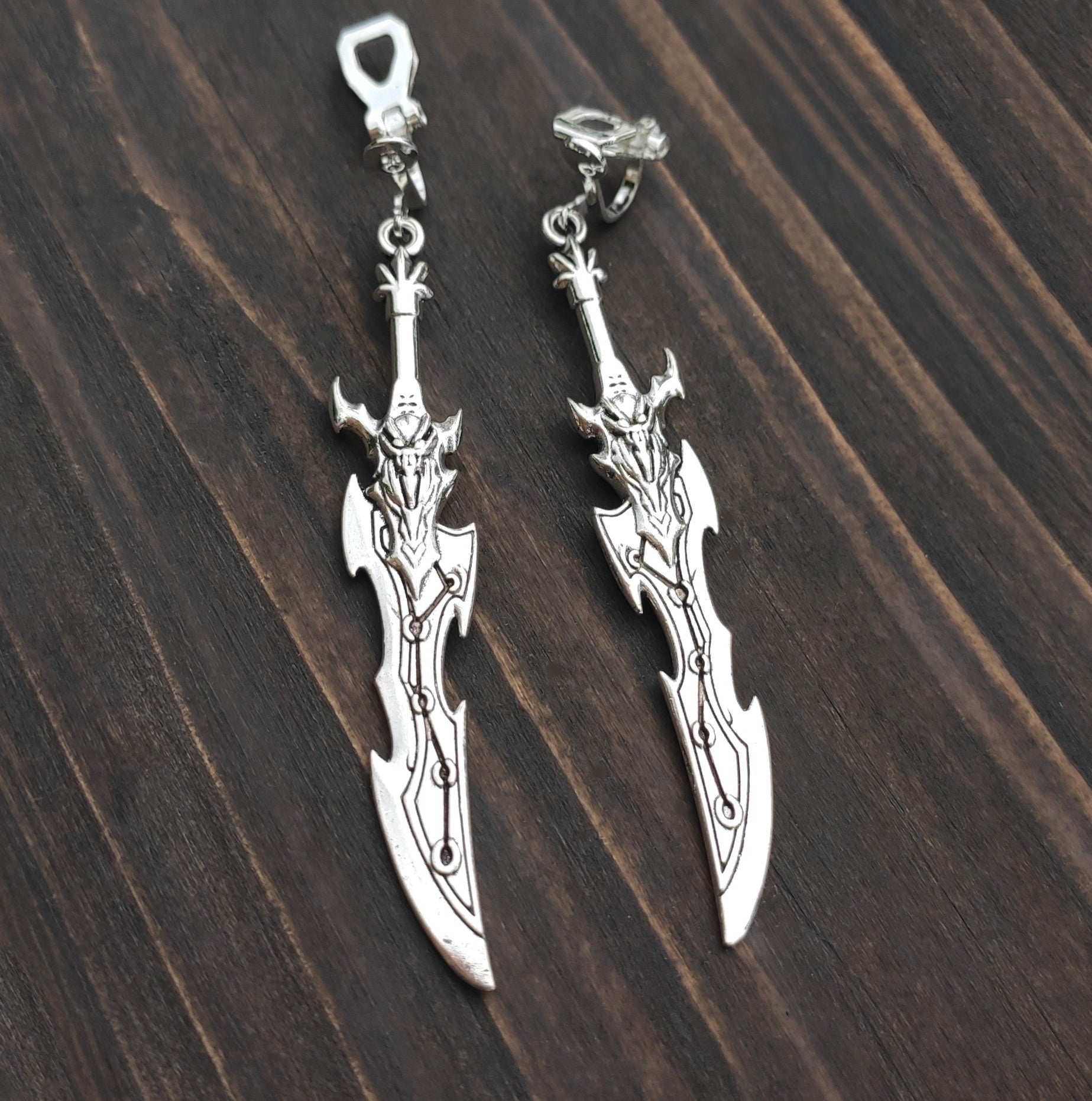 Clip on sword earrings with a silver curved fantasy blade design. A unique gift for RPG players, LARP fans, or gamers.