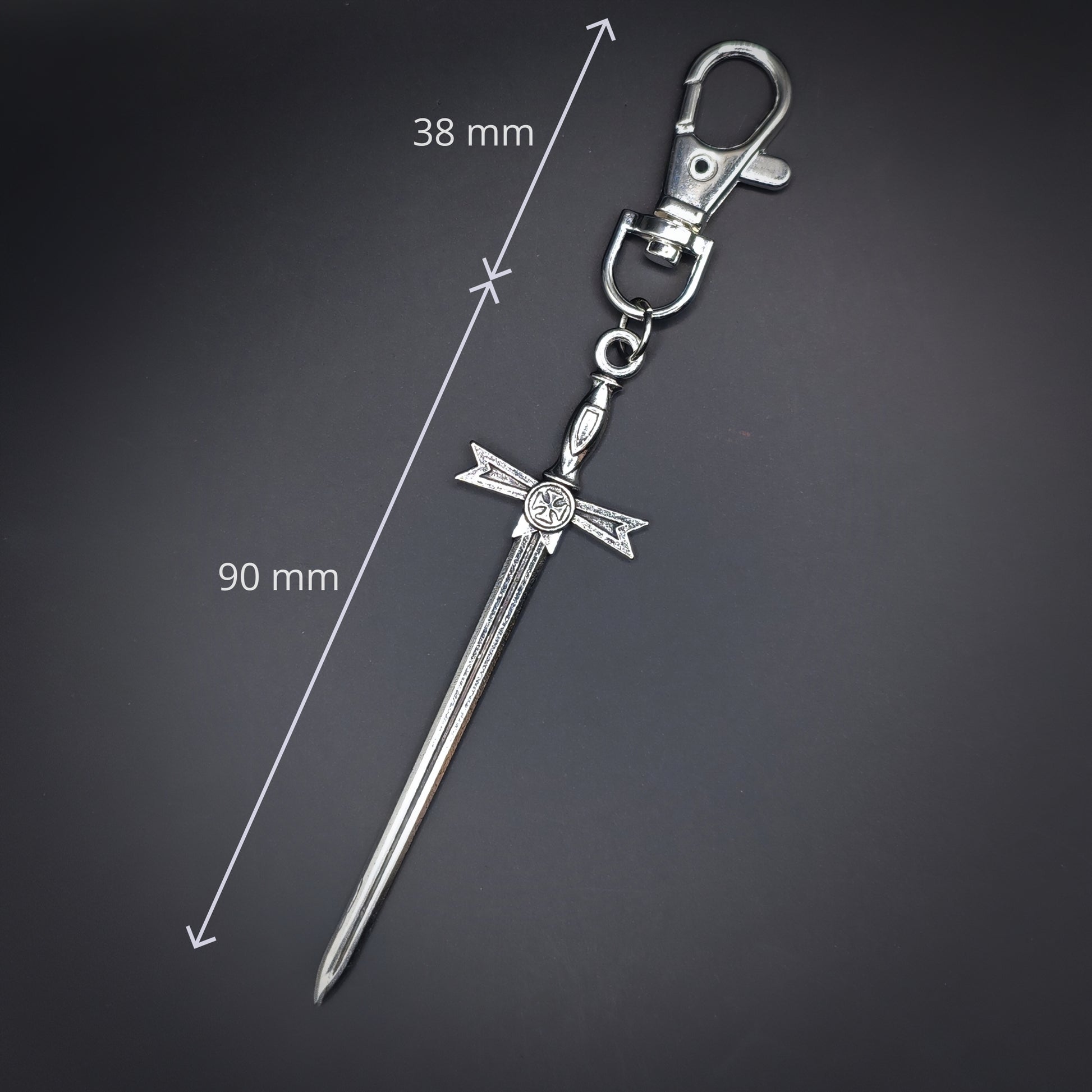 Silver sword-shaped keychain with measurements on a dark background